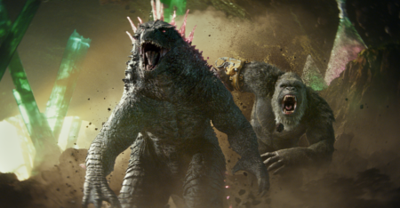 Godzilla og King Kong løber samlet mod kameraet. Både Godzilla og King Kong råber samtidig. King Kong har en robothånd på.
